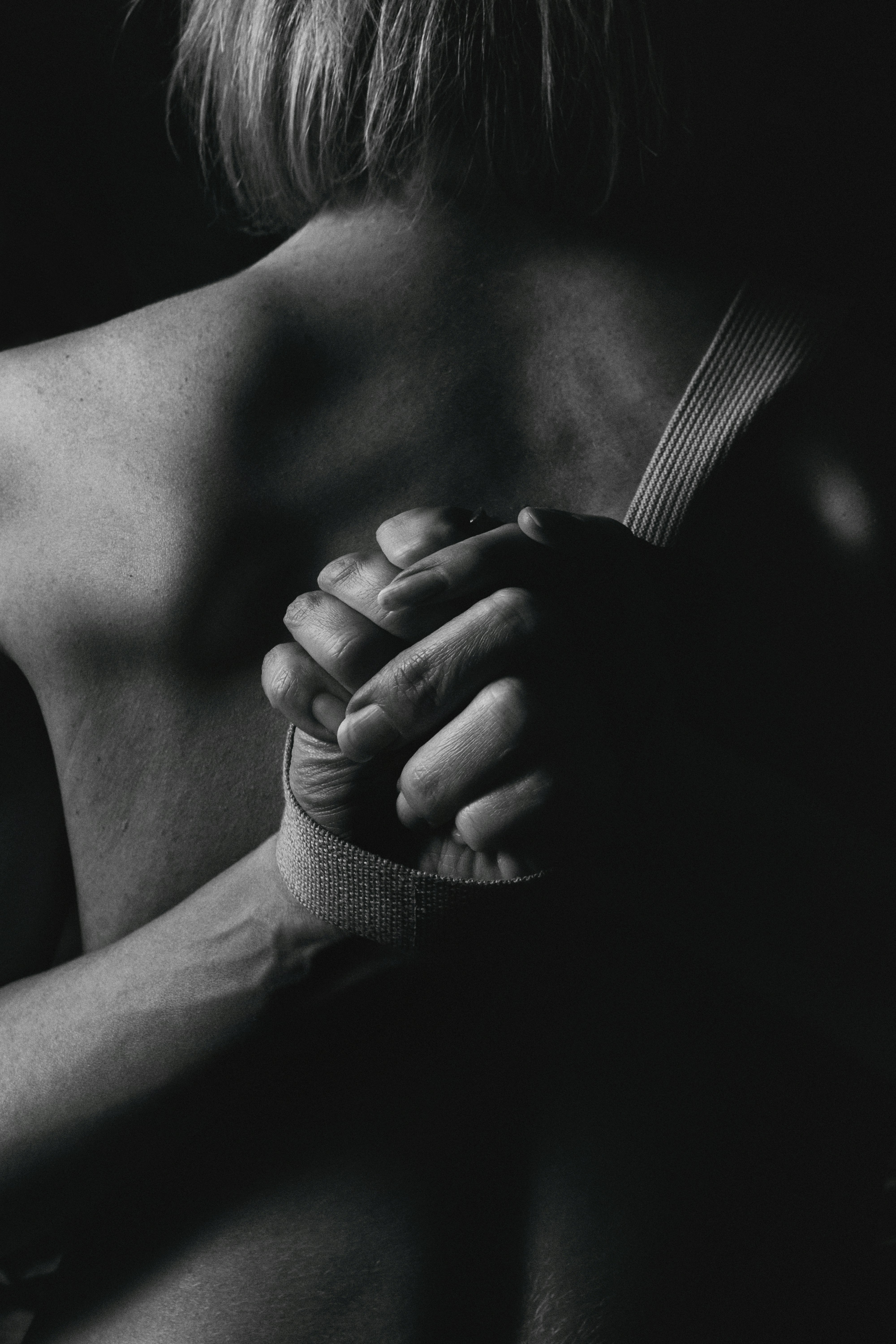 grayscale photo of person's hand tied with nylon strap